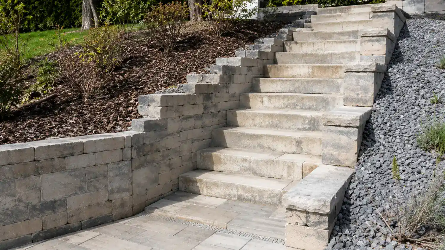 Steintreppe mit Stützmauer und Kiesfläche in einer Gartenanlage mit Hangbefestigung